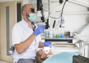 Dentist performing oral surgery under a microscope for a patient at Montana Center for Implants and Dentures, specializing in permanent tooth replacement, dentures, and implants.