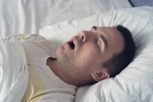 A man experiencing dry mouth at night, a condition that can impact oral health, as addressed by Montana Center for Implants and Dentures.