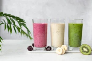 Three nutritious smoothies in glasses—berry, banana, and kiwi—ideal soft foods for a post-op diet after dental implants. Recommended by Montana Center for Implants and Dentures for a smooth recovery.