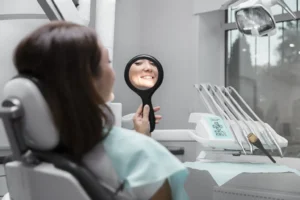 Patient smiling while looking in a mirror during a free consultation at Montana Center for Implants and Dentures for dental implants.