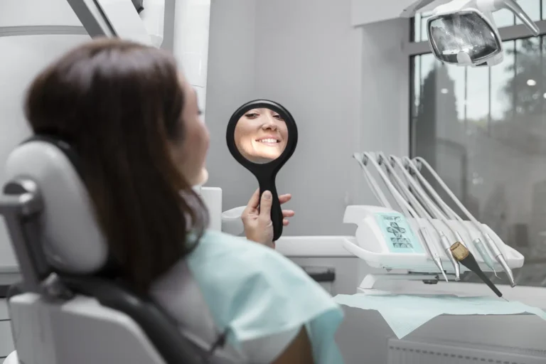 Patient smiling while looking in a mirror during a free consultation at Montana Center for Implants and Dentures for dental implants.