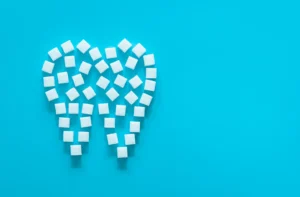 Sugar cubes forming a tooth shape on a blue background, symbolizing the cost of dental implants in Billings, MT.