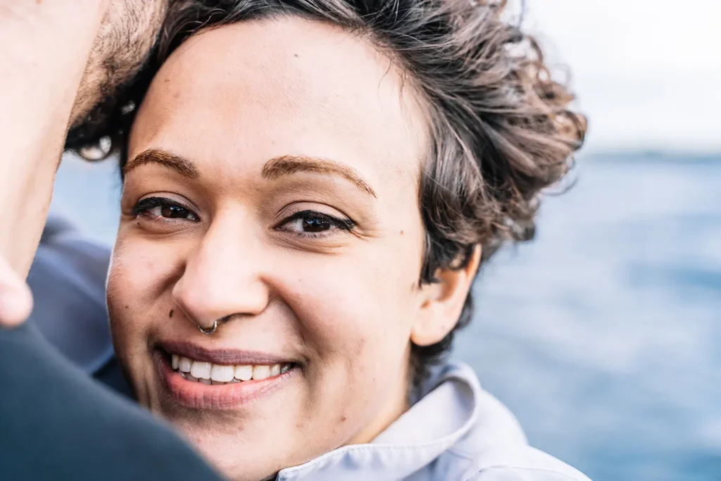 Young woman with curly hair smiling confidently during dental implant healing from Montana Center for Implants and Dentures.