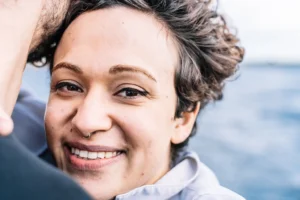 Young woman with curly hair smiling confidently during dental implant healing from Montana Center for Implants and Dentures.