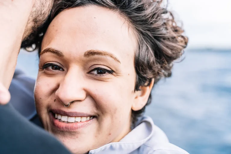 Young woman with curly hair smiling confidently during dental implant healing from Montana Center for Implants and Dentures.